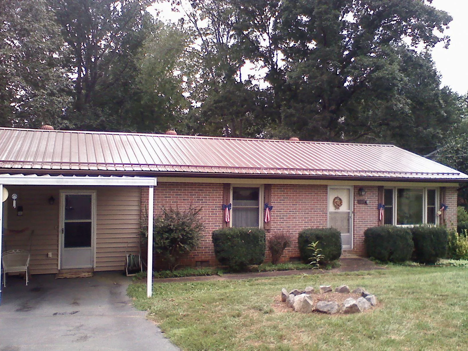 Bronze metal roof and carport on a brick ranch home — Roof Repair work by our crew in Roosevelt
